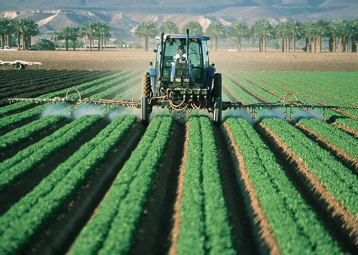 Farmer in tractor spraying field